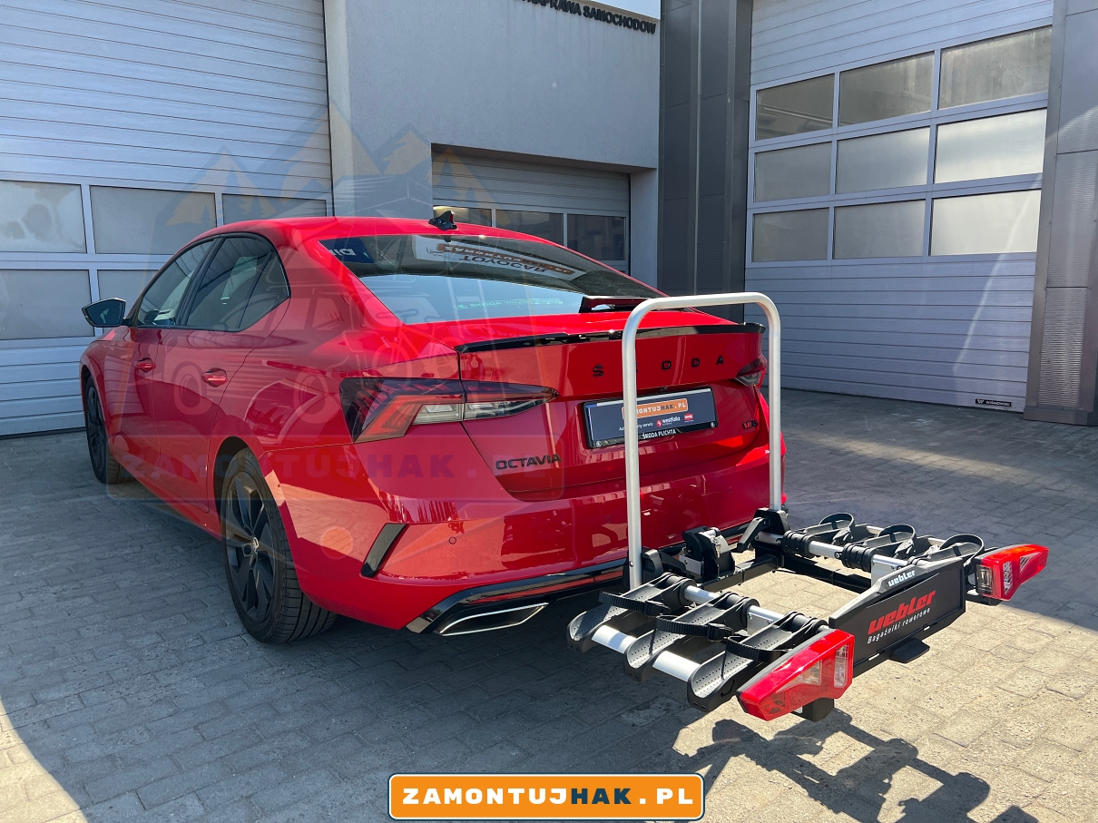 Czerwona Skoda Octavia IV RS z hakiem holowniczym i bagażnikiem rowerowym Uebler i31 na haku holowniczym